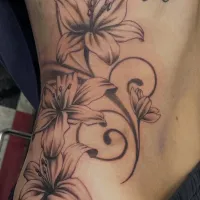 Fine line lilies and trailing vines across the ribs — by Gabriel Gonzalez
